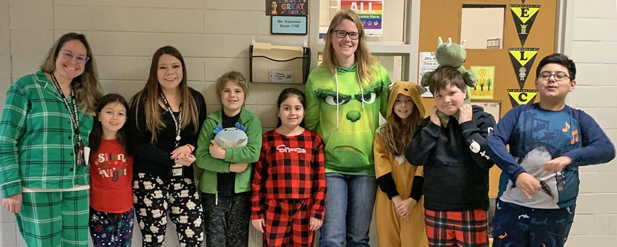 Photo of staff and students dressed in pajamas standing together in the hallway