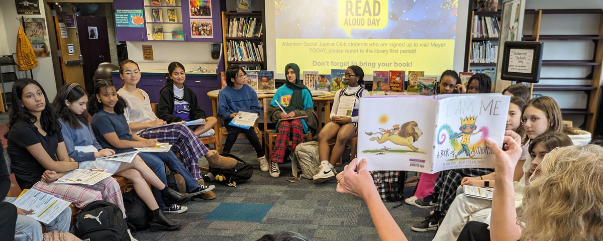 Photo of middle school librarian reading to students in the school library